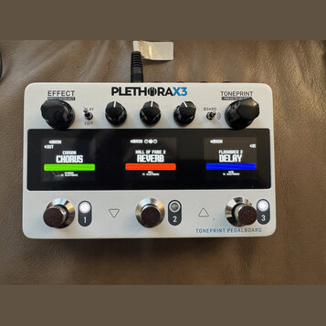 Bílý efektový pedál s nápisem PLETHORA X3 a TONEPRINT PEDALBOARD. Zařízení má tři ovládací knofíky nahoře, tři displeje zobrazující efekty CORONA CHO…
