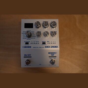 Stříbrný efektový pedál s nápisy BOSS DIGITAL DELAY DD-200. Zařízení má šest otočných knoflíků, několik přepínačů a čtyři kontrolní LED diody. V doln…