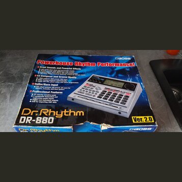 Kartonová krabice s obrázkem elektronického bicího automatu. Na obalu je nápis Powerhouse Rhythm Performance!, značka BOSS a model Dr. Rhythm DR-880…