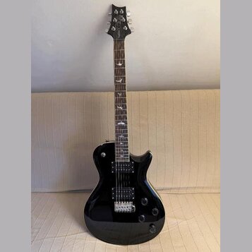 Černá elektrická kytara s dvojstupňovitým tělem a tmavým hmatníkem. Na hlavě je viditelné logo "Epiphone". Hmatník obsahuje bílé vložky ve tvaru pták…