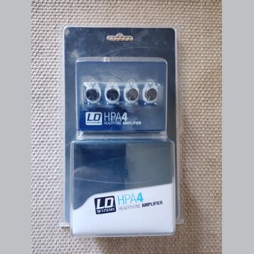 Modrý sluchátkový zesilovač v originálním plastovém balení. Na přístroji i na krabici je bílý nápis LD SYSTEMS HPA4 HEADPHONE AMPLIFIER. Zařízení má…