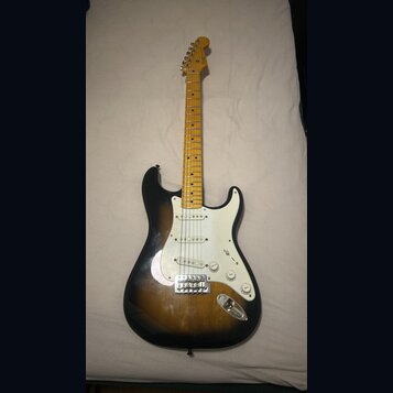 Elektrická kytara s tónem těla v provedení sunburst a bílým pickguardem. Na hlavě hředu je viditelné logo Fender. Nástroj má javorový hmatník a tři s…