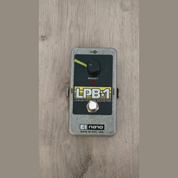 Kytarový efekt v šedém kovovém šasi s černým ovládacím panelem. Na panelu je jeden otočný knoflík, červená kontrolka a nápisy LPB-1 LINEAR POWER BOOS…