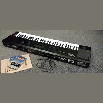 Černý klavierní syntetizátor s bílými a černými klávesami. Na předním panelu jsou nápisy Roland W-30 a Roland MUSIC WORKSTATION. Vedle nástroje je po…